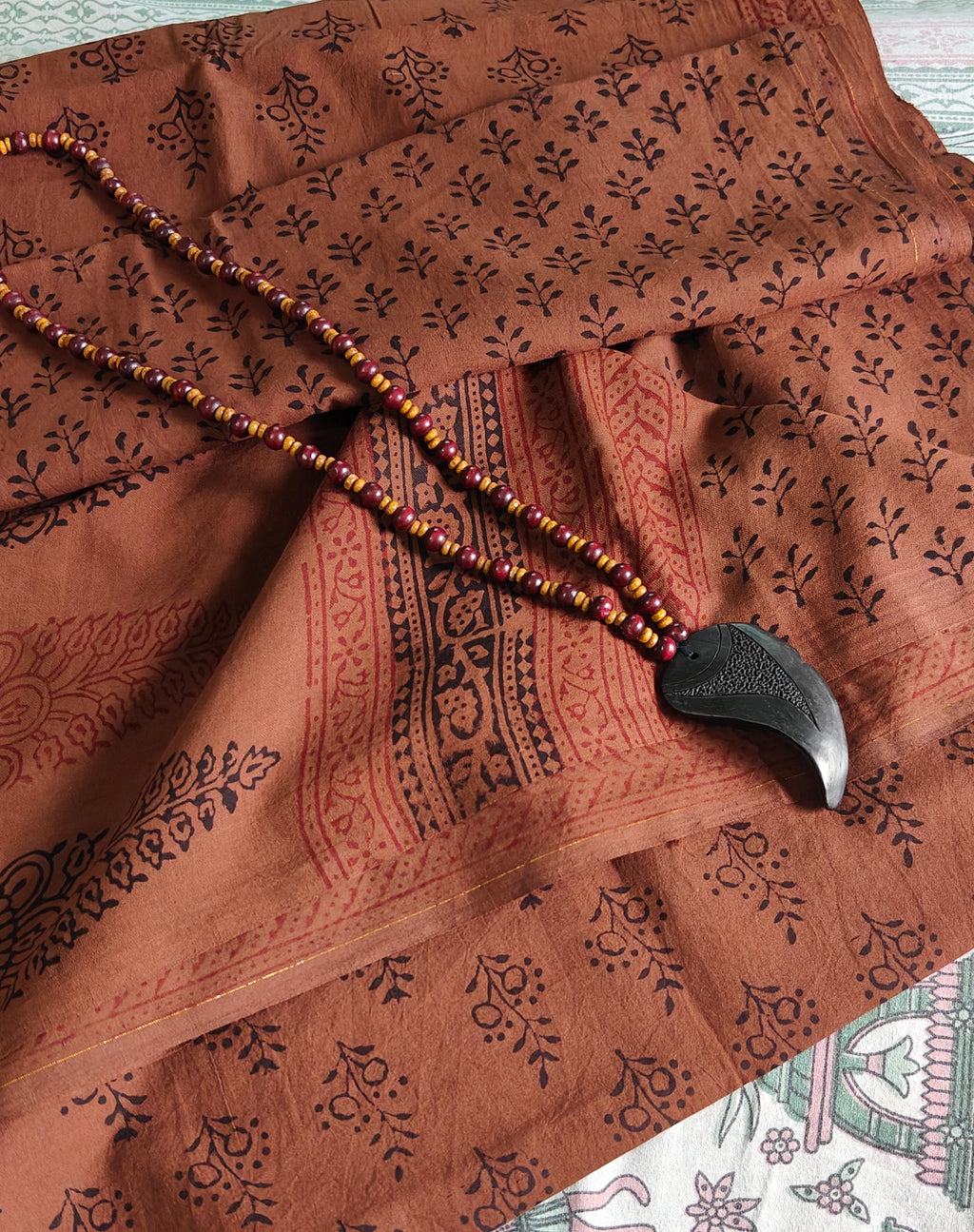 Artisan-made Dola silk saree featuring traditional Dhar Bagh wooden block prints with red and black floral motifs and Brownish red accents.