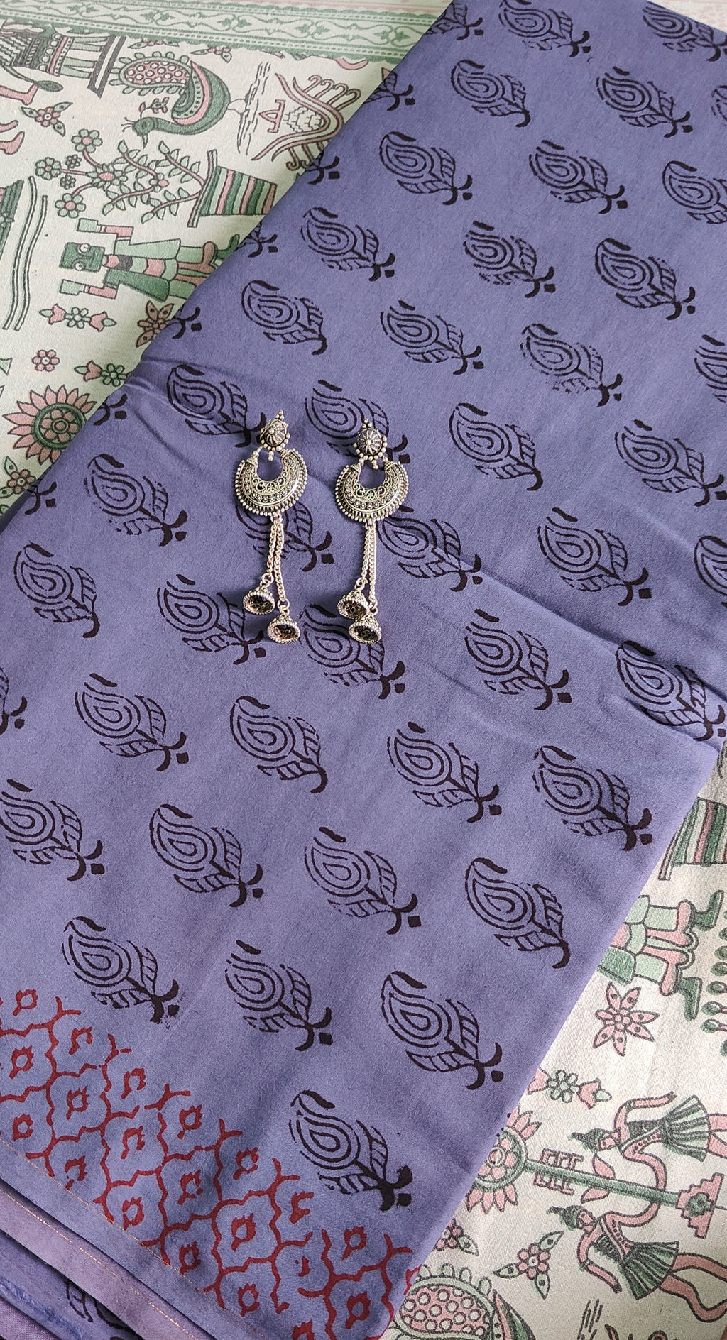 Handmade Purple fabric with Bagh print with  black patterns and silver earrings on a patterned surface