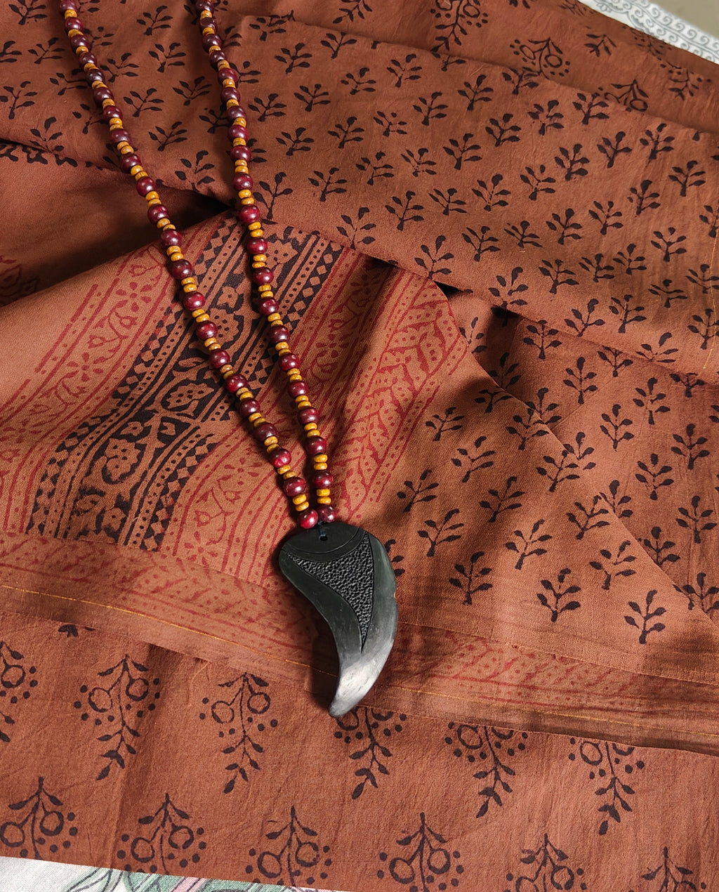 Artisan-made Dola silk saree featuring traditional Dhar Bagh wooden block prints with red and black floral motifs and vibrant red accents.