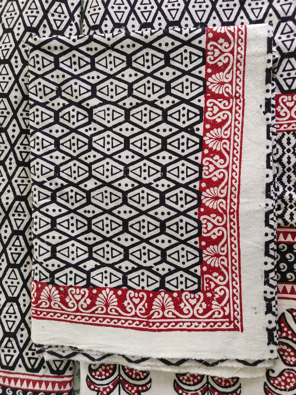Black and white geometric pattern with red accents on a fabric swatch