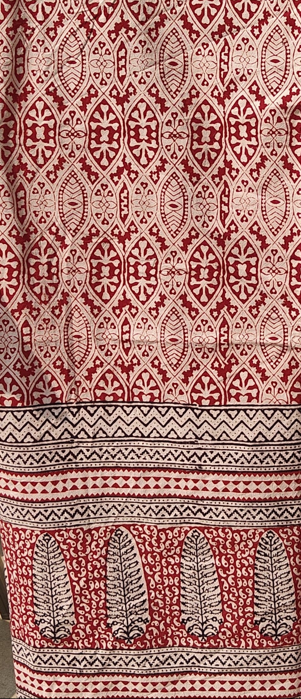 Close-up of a fabric with a red and beige geometric pattern.Set of handmade Bagh block print in traditional offwhite with red  big  block and madder red pattern with big leaf bold border three curtains