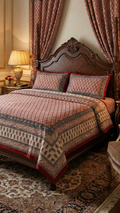 Decorative bedroom with a bed covered in red patterned bedding, flanked by lamps and ornate curtains.