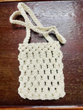 Minimalist macrame mobile sling bag with a long crossbody strap and a secure geometric knot pattern for smartphones