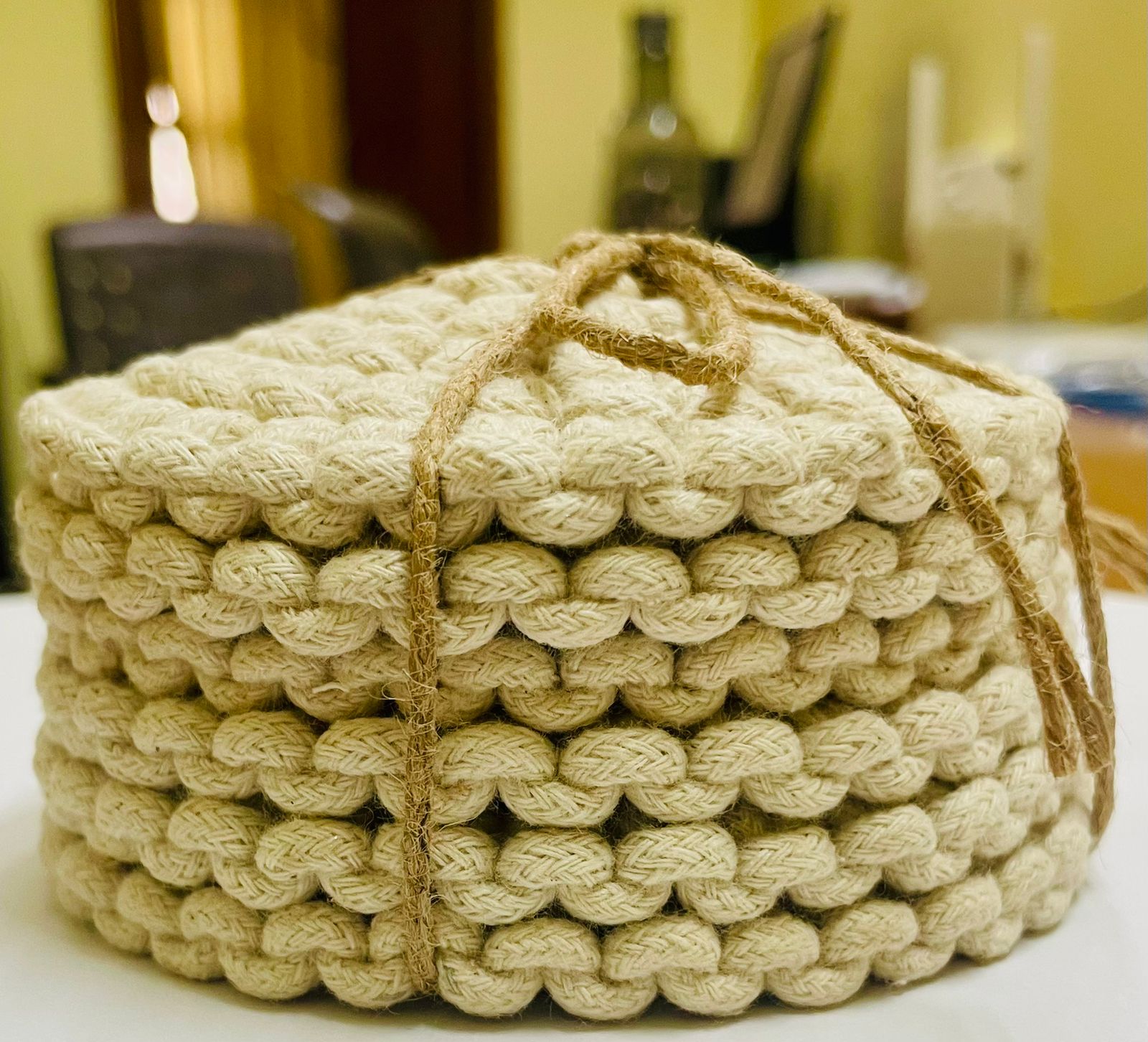 Set of circular macrame coasters , used as boho mug rugs on a wooden coffee table
