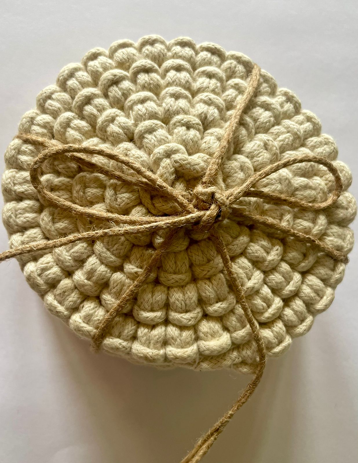 Set of circular macrame coasters , used as boho mug rugs on a wooden coffee table