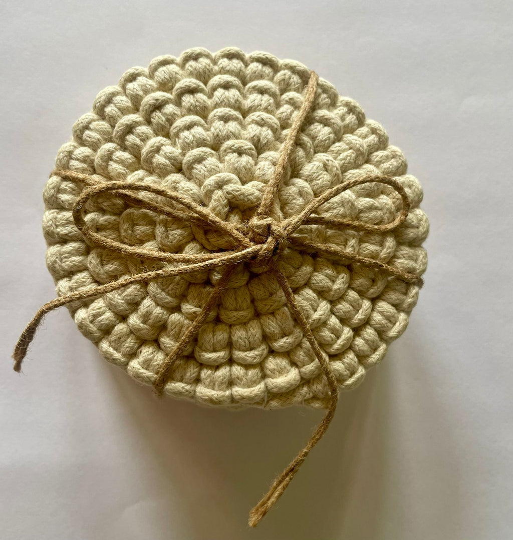 Set of circular macrame coasters , used as boho mug rugs on a wooden coffee table