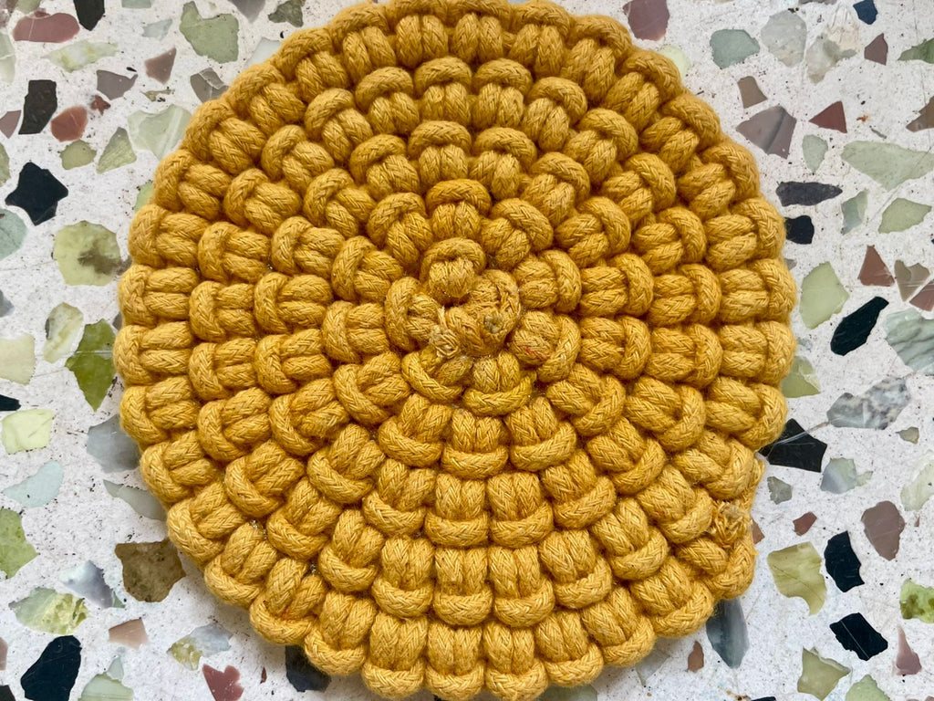 Set of circular macrame coasters , used as boho mug rugs on a wooden coffee table