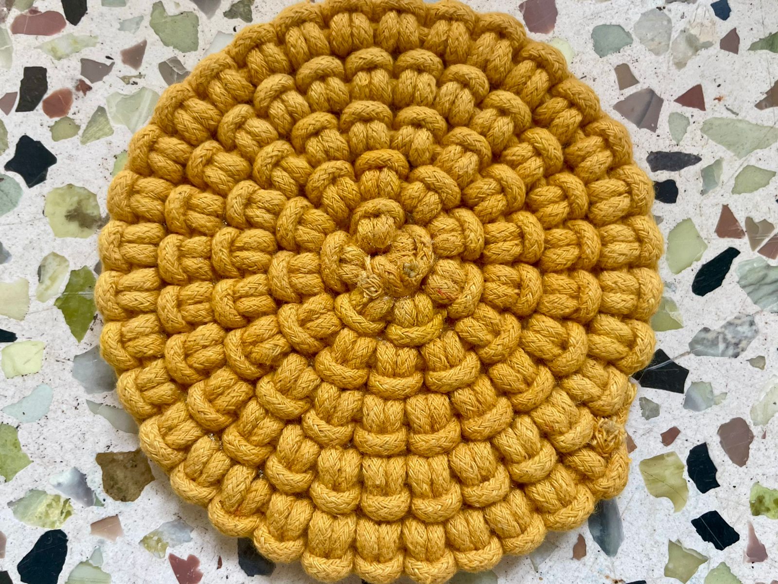 Set of circular macrame coasters , used as boho mug rugs on a wooden coffee table
