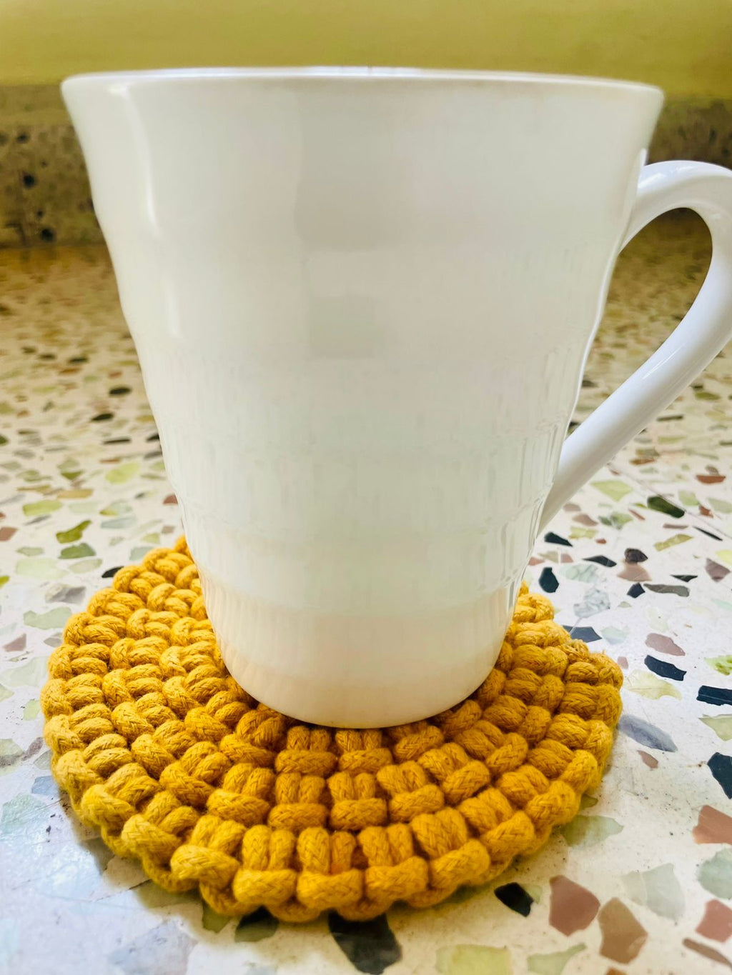 Set of circular macrame coasters , used as boho mug rugs on a wooden coffee table
